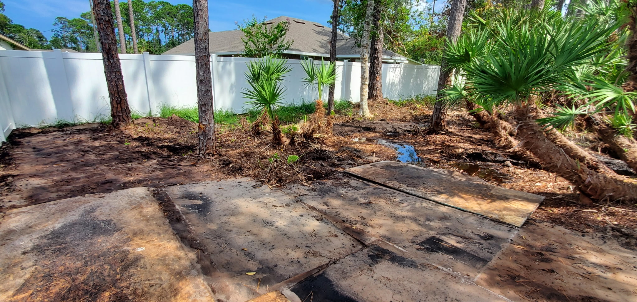 Backyard land clearing with ground protection mats down near a fence line