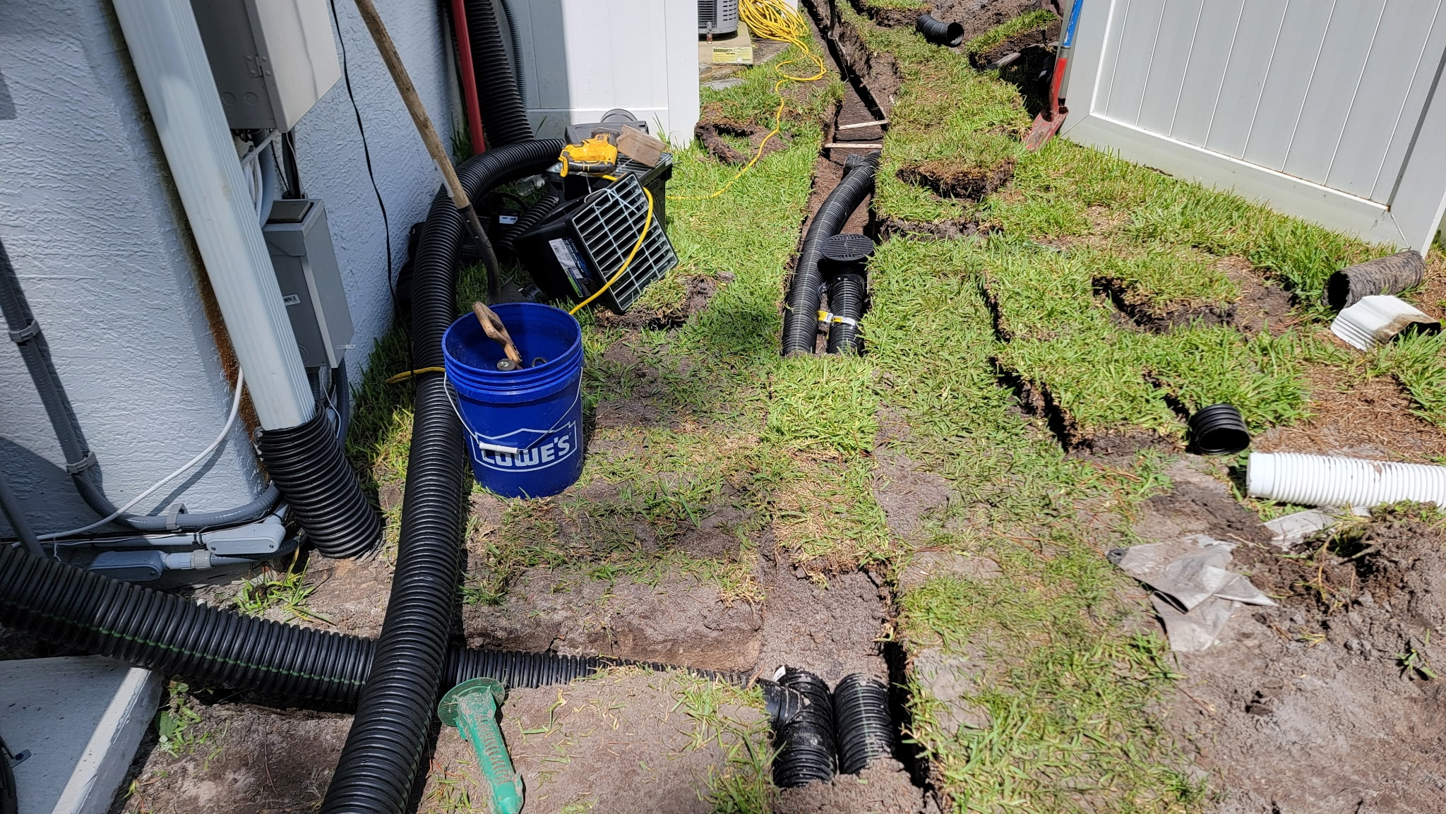 Drain pipe trench installation running alongside a house