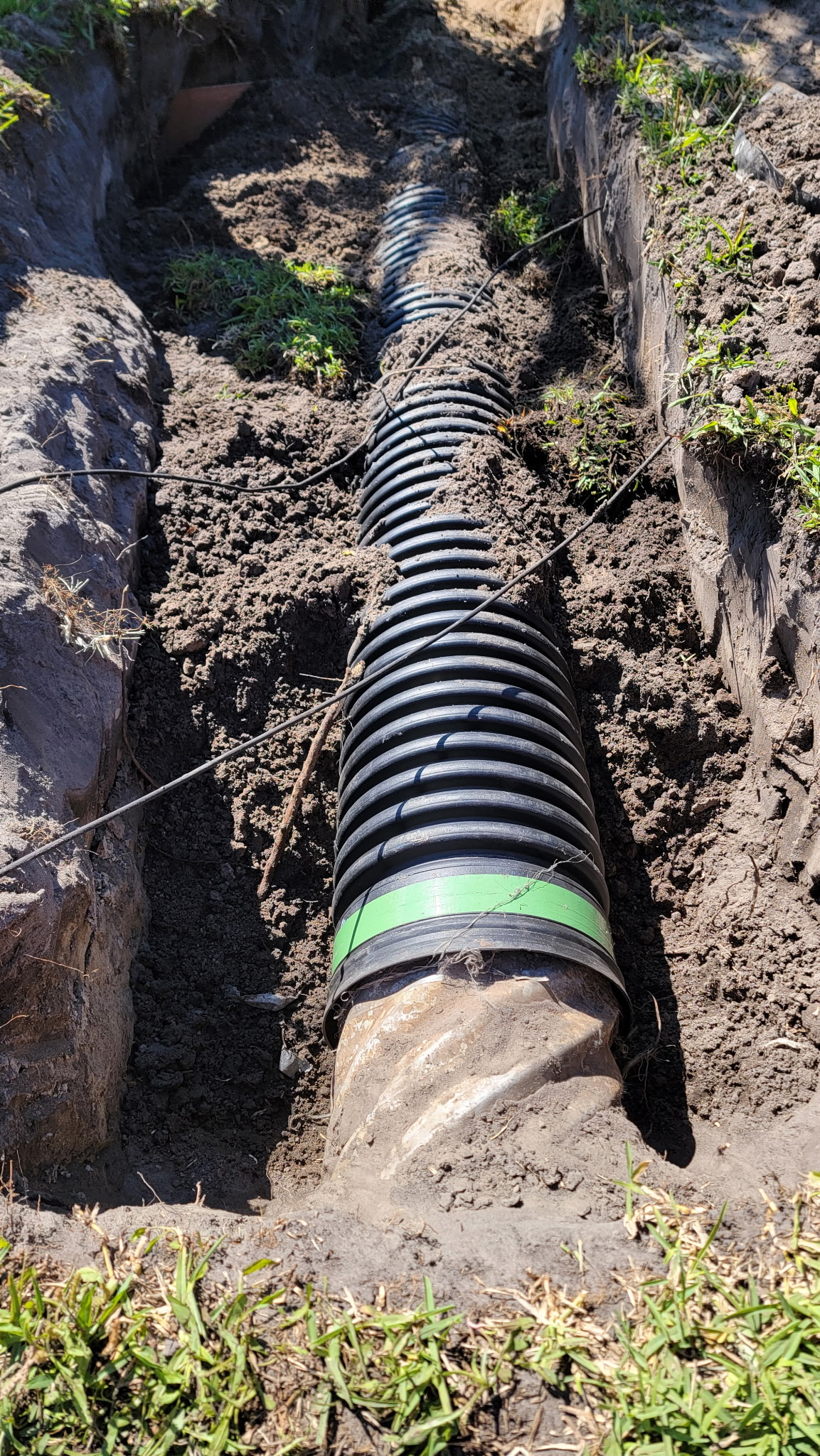 Crew hand-digging a French drain trench in a Palm Coast backyard