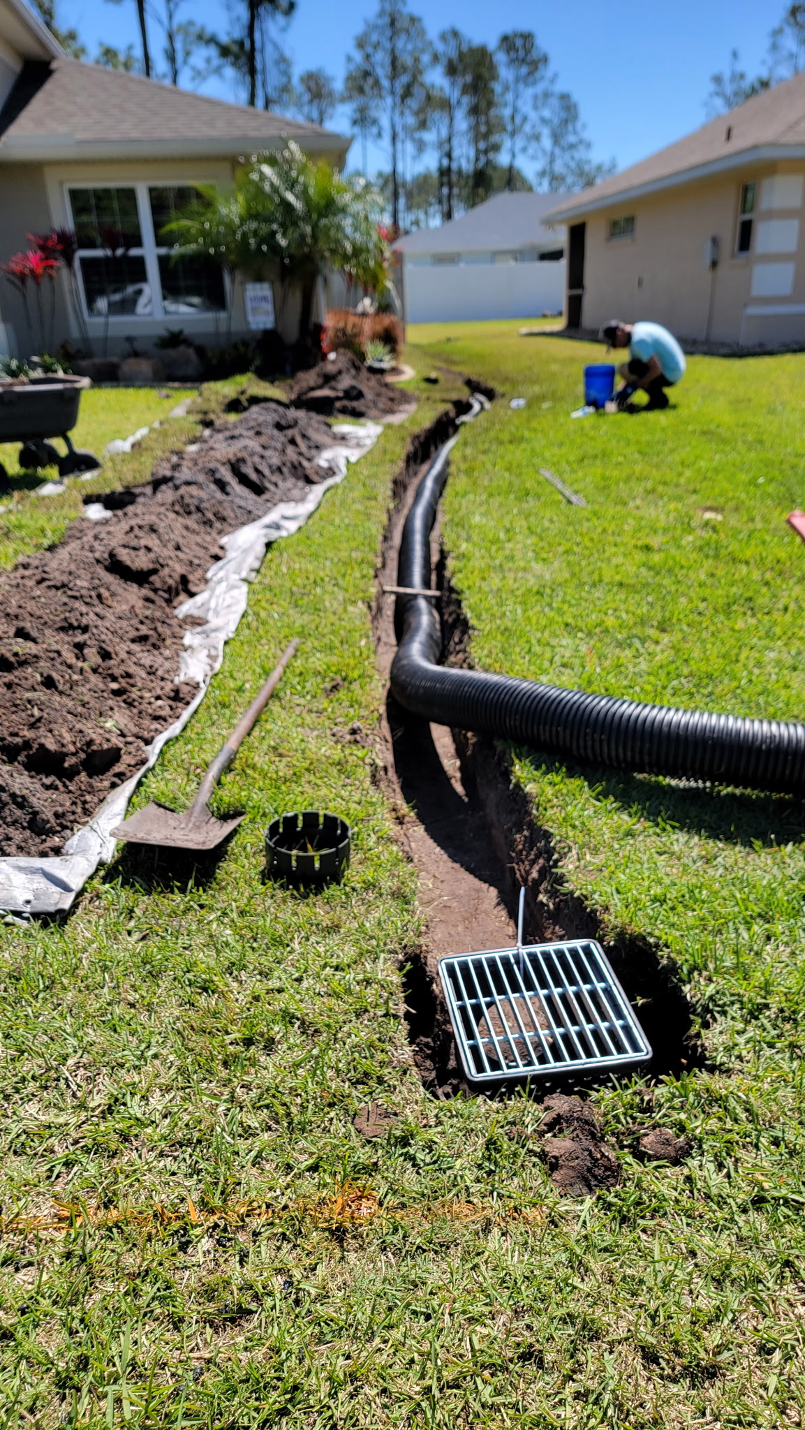Crew installing a new catch basin and drain pipe in a front yard