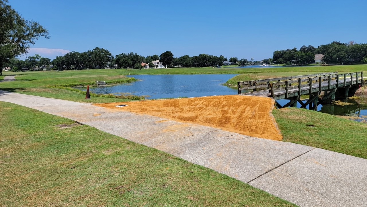 Freshly graded fill along a golf course cart path near a bridge