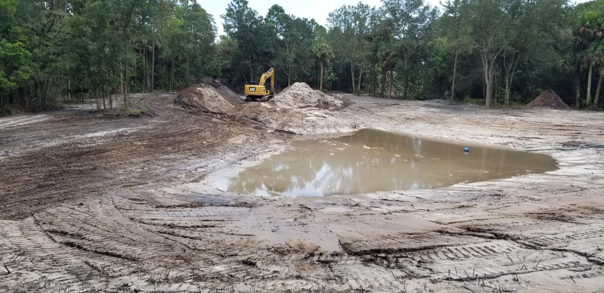 Wide view of a pond excavation with fill piles ready for grading