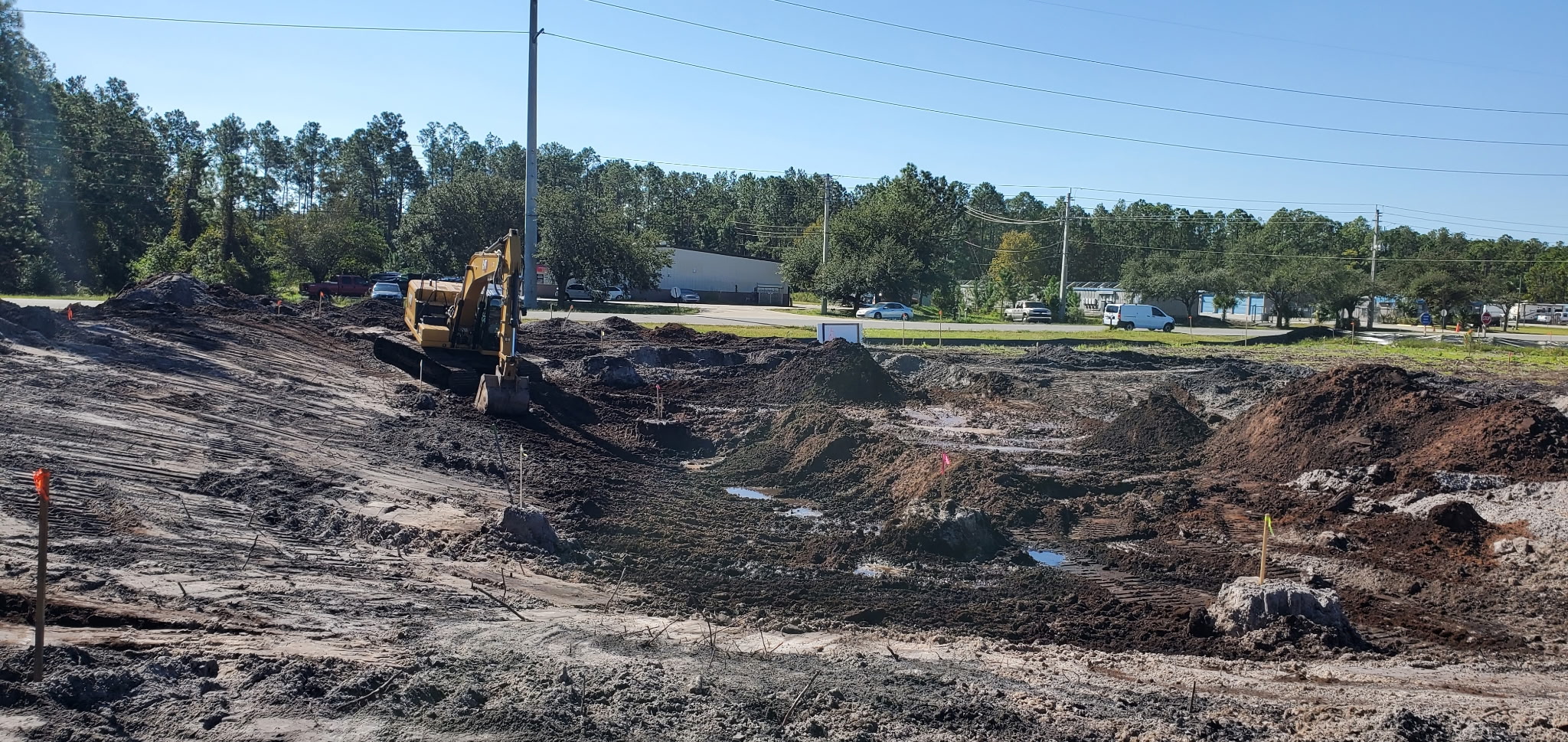 Large retention pond excavation near a business corridor with excavator at work