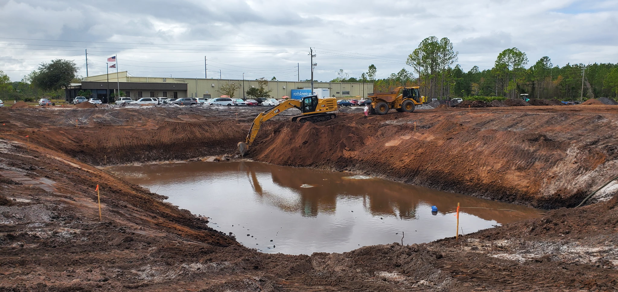 Excavator and dump truck excavating a large commercial retention pond