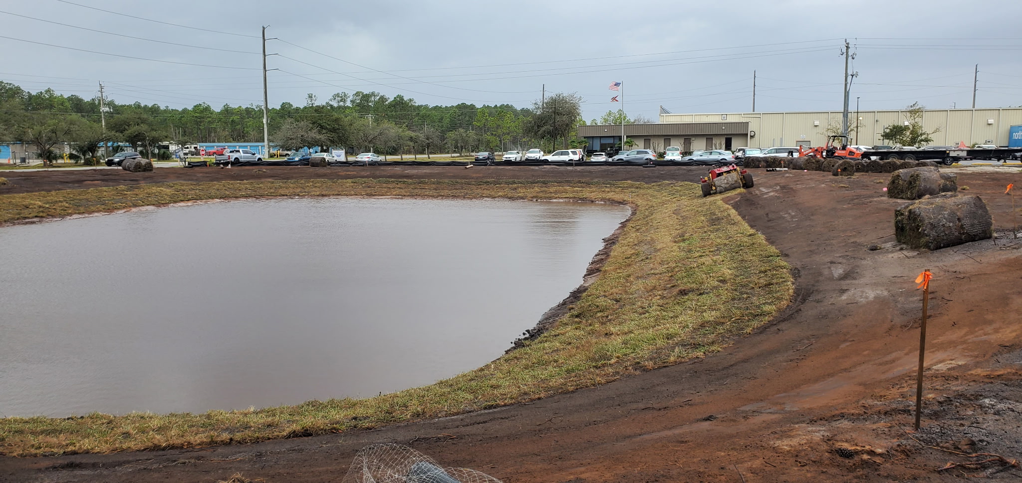 Excavator shaping a pond bank on a wooded Flagler County lot