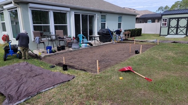 Crew grading and prepping the base for a new brick paver patio
