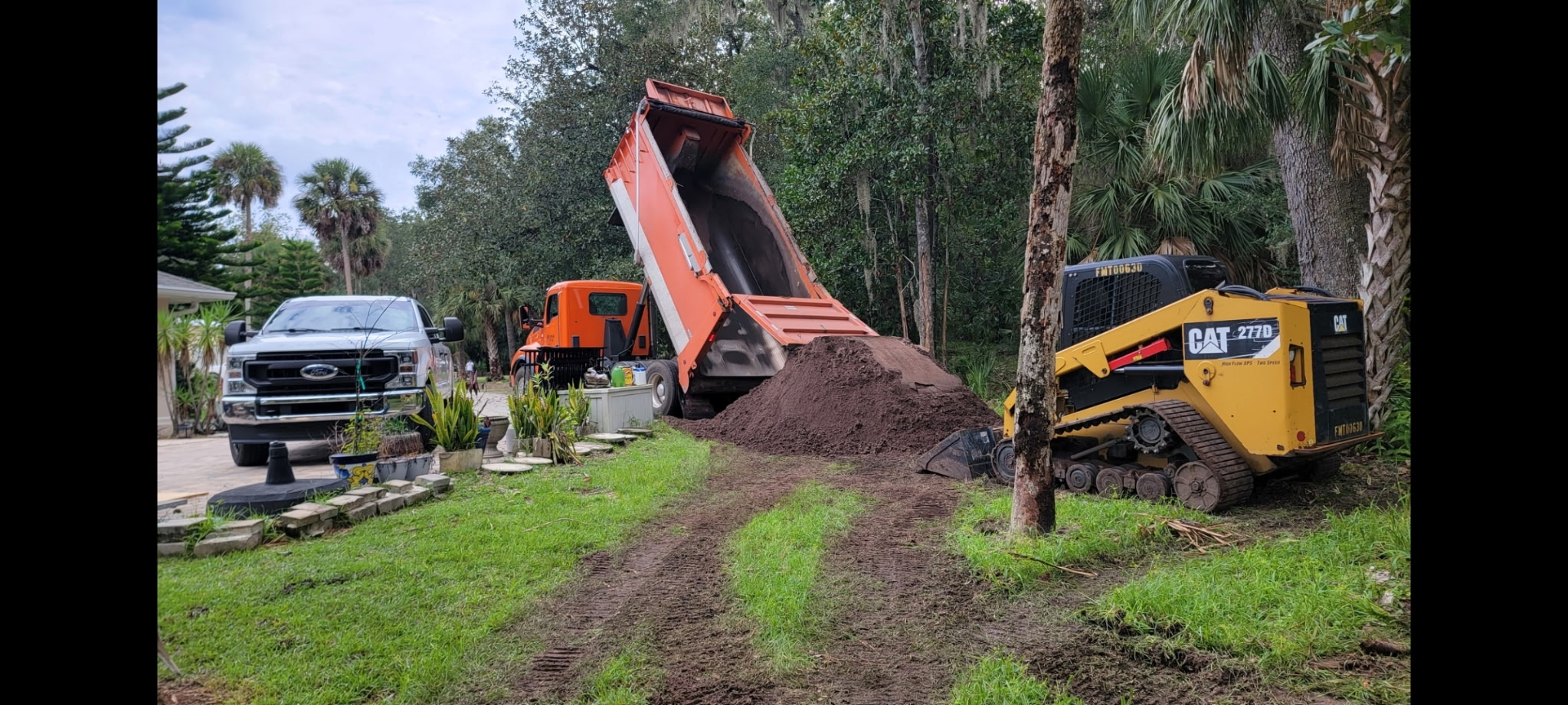 Precision Land Grading crew delivering fill dirt and grading a residential yard in Palm Coast, FL