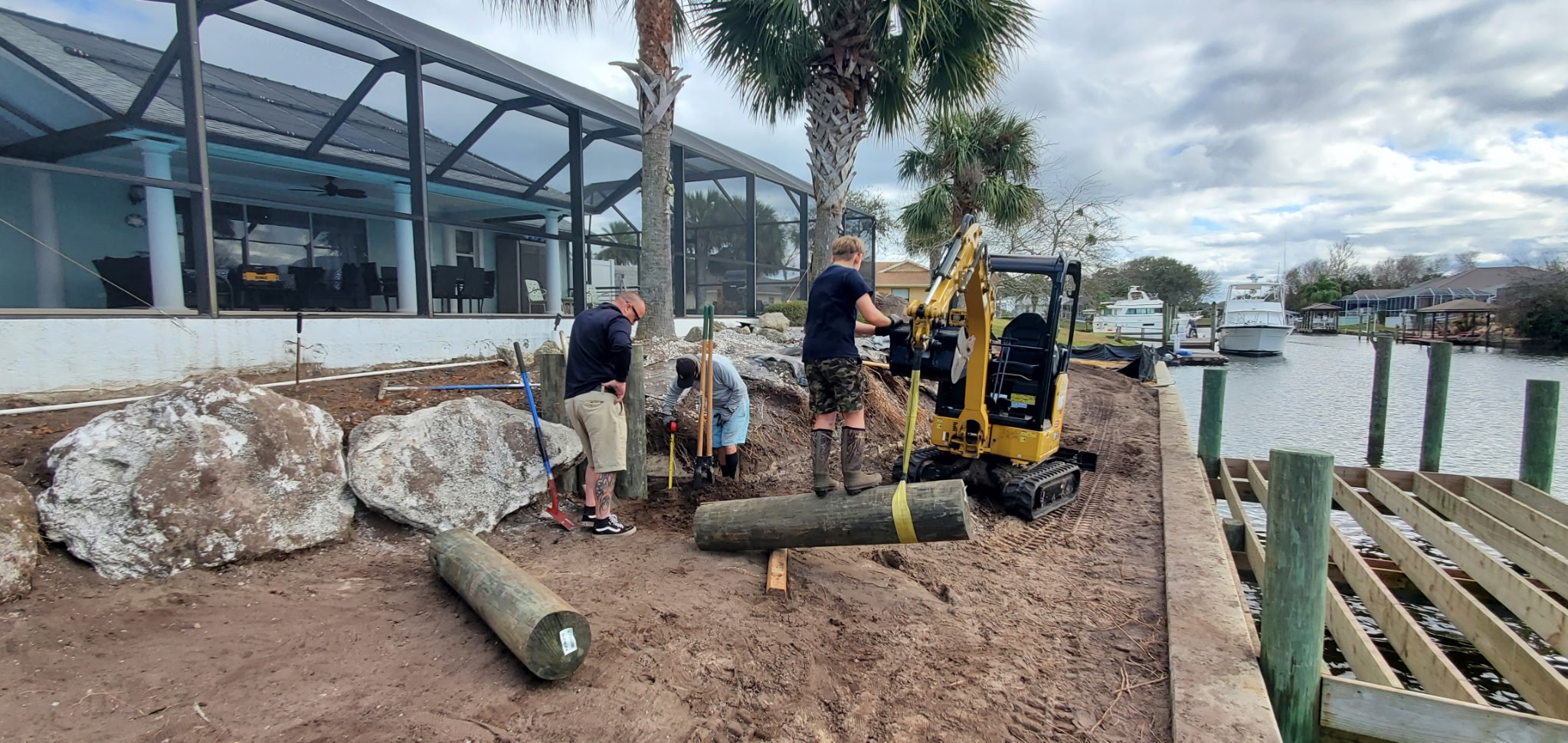 Mini excavator performing waterfront property excavation near a dock