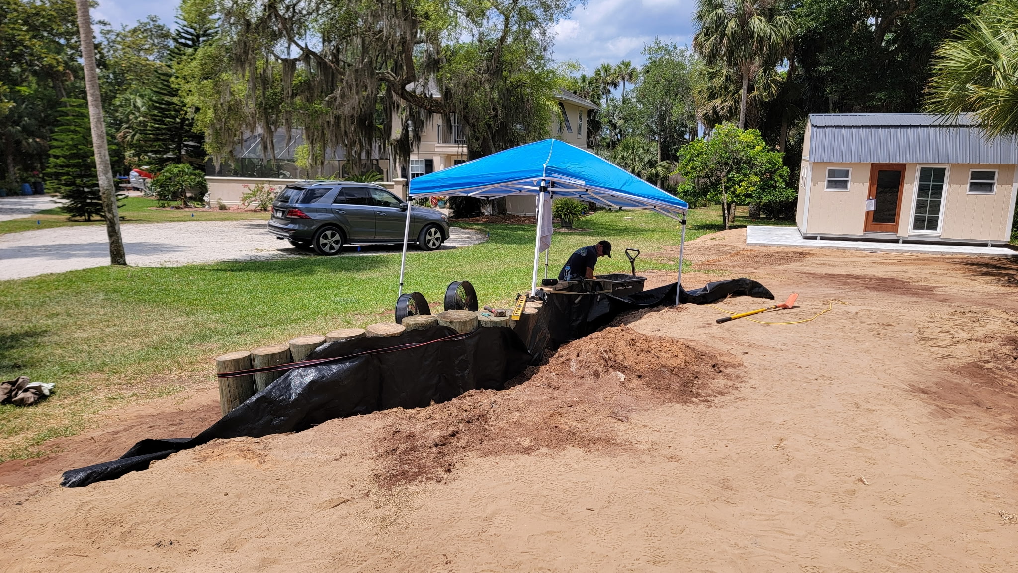 Timber retaining wall and pond liner installation in a backyard