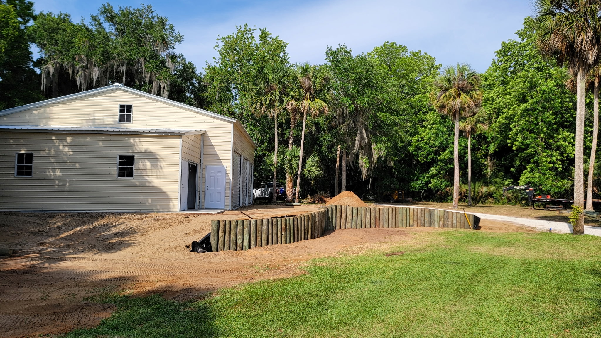 Finished timber retaining wall along a metal workshop building