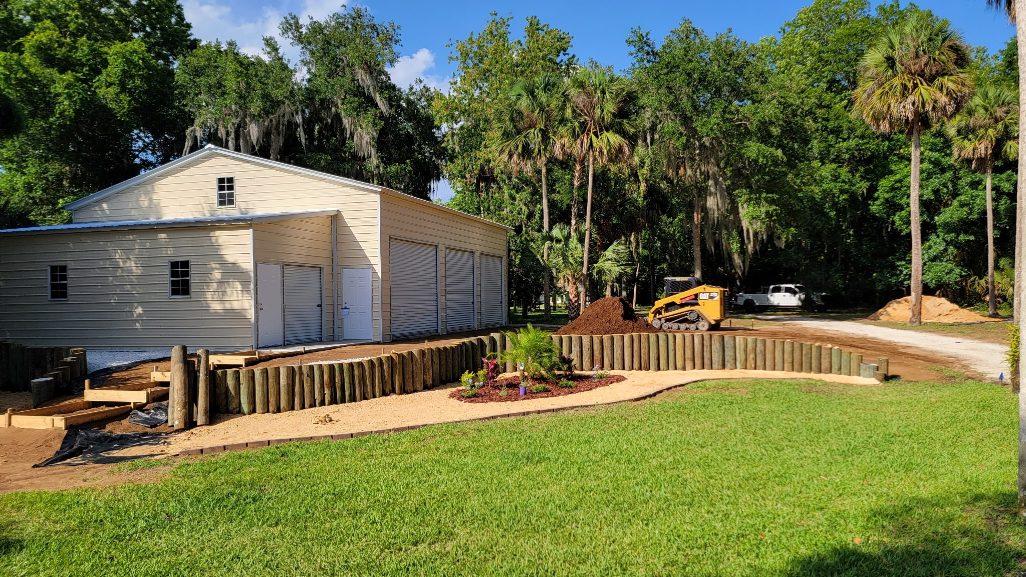 New timber retaining wall and landscape bed installed beside a detached garage